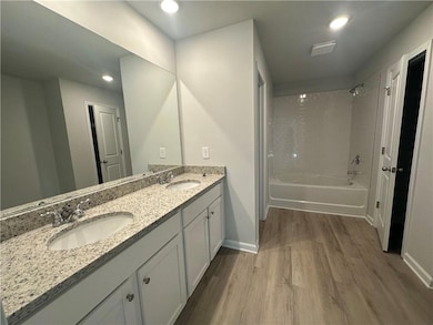 Full bathroom featuring a sink, baseboards, wood f