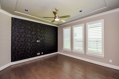 Home office features tray ceiling, feature wall, and plantation shutters.