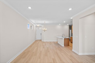 Interior space featuring ornamental molding, a sink, an inviting chandelier, and light wood-style floors
