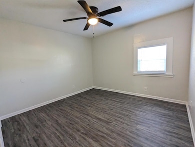 Spare room featuring dark wood-style floors and ceiling fan