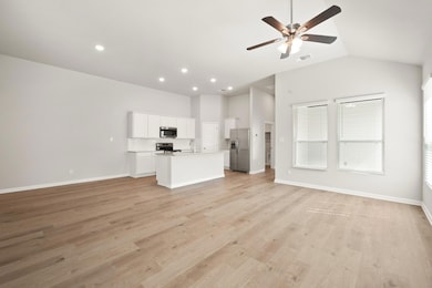 Unfurnished living room featuring vaulted ceiling, a ceiling fan, light wood-type flooring, and recessed lighting