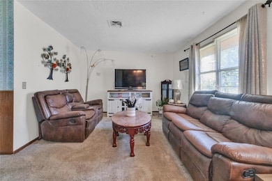 Carpeted living area featuring a textured ceiling