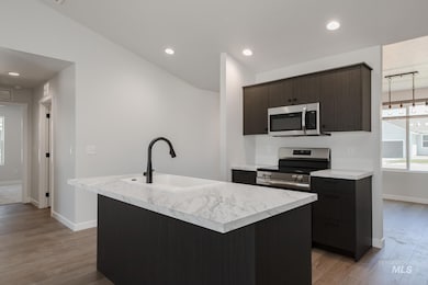 Kitchen with stainless steel appliances, light wood-style floors, light countertops, a kitchen island with sink, and recessed lighting