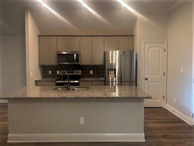 Kitchen featuring appliances with stainless steel finishes, gray cabinets, light stone counters, vaulted ceiling, and backsplash