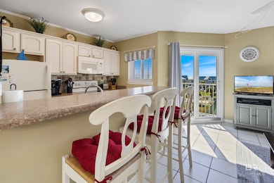 Kitchen with light tile patterned flooring, tasteful backsplash, white appliances, a textured ceiling, and a kitchen breakfast bar