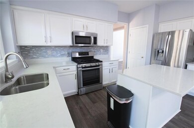 Kitchen with appliances with stainless steel finishes, decorative backsplash, dark wood-style floors, and white cabinets