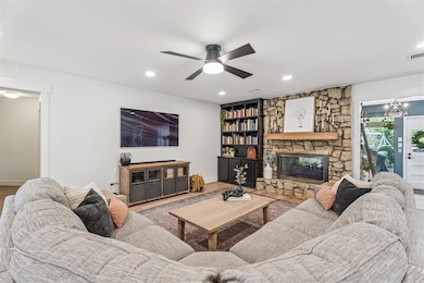 Living area featuring wood finished floors, a fireplace, recessed lighting, a ceiling fan, and a chandelier