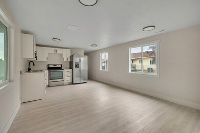 Kitchen with white cabinetry, light countertops, appliances with stainless steel finishes, light wood finished floors, and open floor plan