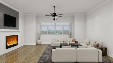 Living room with a warm lit fireplace, wood finished floors, crown molding, and a ceiling fan