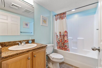 Full bath featuring vanity, shower / bath combo, a textured ceiling, and tile patterned floors