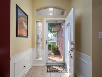 Entryway featuring wainscoting, a decorative wall, and light tile patterned floors