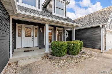 Entrance to property with a garage, a shingled roof, and covered porch