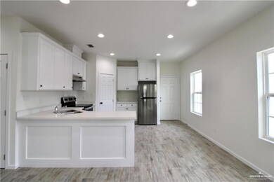 Kitchen with white cabinets, appliances with stainless steel finishes, recessed lighting, light wood-type flooring, and a peninsula