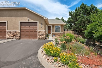 View of front of home with stucco siding, stone siding, an attached garage, and asphalt driveway