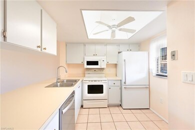 Kitchen with white appliances, a sink, a ceiling fan, light countertops, and light tile patterned floors