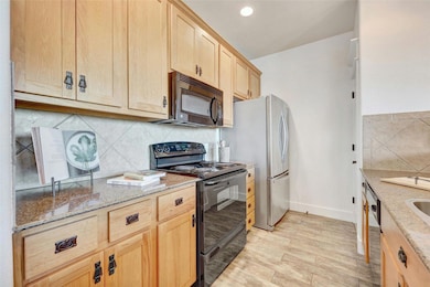 Kitchen featuring black appliances, light brown c