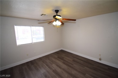 Unfurnished room with dark wood-type flooring and a ceiling fan