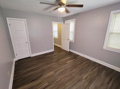 Unfurnished bedroom featuring dark wood-type flooring and ceiling fan