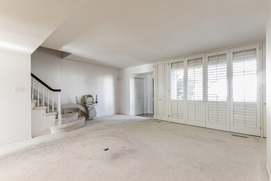 Unfurnished living room with carpet flooring and stairway
