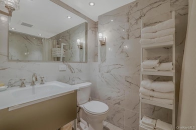 Bathroom featuring tile walls, vanity, recessed lighting, and a marble finish shower