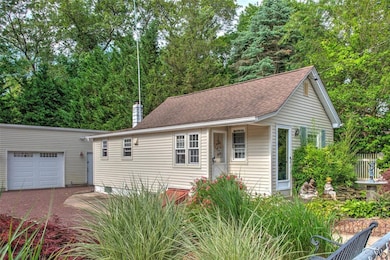 View of front of property with a garage, a chimney, an outbuilding, and roof with shingles