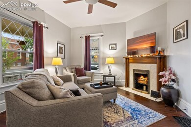 Living area with a fireplace, wood finished floors, and baseboards