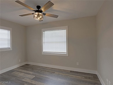 Empty room with dark wood-style flooring and a ceiling fan