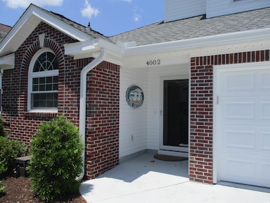 View of exterior entry featuring a shingled roof, brick siding, and an attached garage