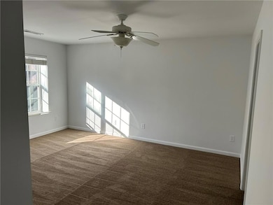 Empty room featuring dark colored carpet and ceiling fan