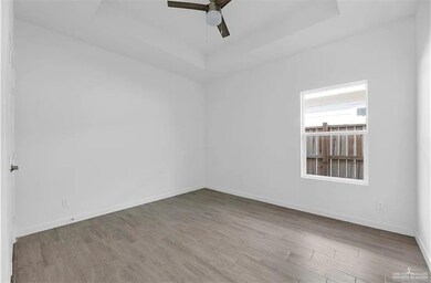 Spare room featuring a tray ceiling, light wood-style floors, and ceiling fan