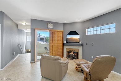 Tiled living area featuring baseboards and a fireplace
