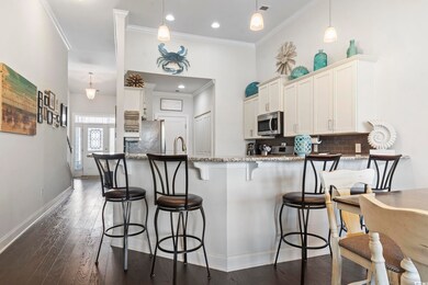 Kitchen with stainless steel appliances, ornamental molding, tasteful backsplash, white cabinetry, and a peninsula