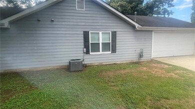 View of side of property featuring a garage, concrete driveway, and a yard