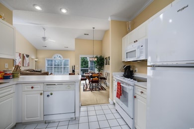 Kitchen with white cabinets, lofted ceiling, white