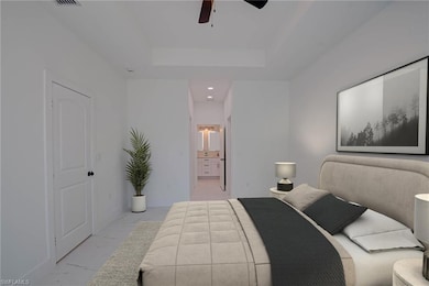 Bedroom featuring light marble finish flooring, a tray ceiling, ceiling fan, and connected bathroom