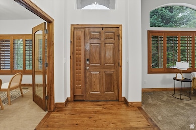 Carpeted foyer entrance with wood finished floors and a towering ceiling