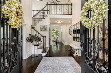 Entryway with stairway, wood finished floors, and a towering ceiling