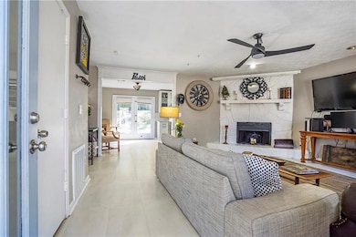 Living room featuring ceiling fan, french doors, and a fireplace