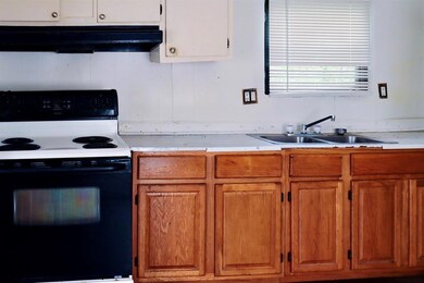 Kitchen with electric stove, under cabinet range hood, a sink, and light countertops