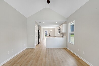 Vaulted ceilings in living room open to functional white kitchen