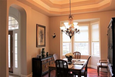 A close up view of the formal dining shows off the Cherry hardwood floors, the double tray ceiling, the bay foundation with large windows & tall ceilings.
