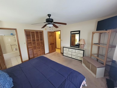 Bedroom with a ceiling fan, ensuite bath, and a closet