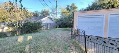 Fenced backyard featuring an outbuilding and a garage