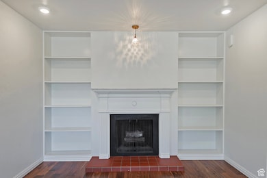 Unfurnished living room featuring recessed lighting, a fireplace with raised hearth, and dark wood finished floors