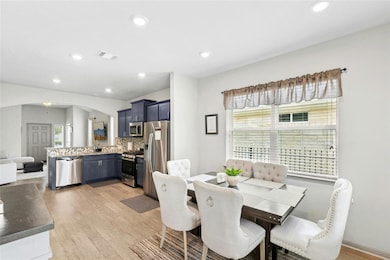 Dining space with light wood-style floors, arched walkways, and recessed lighting