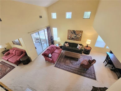 Living room with high vaulted ceiling, carpet, and