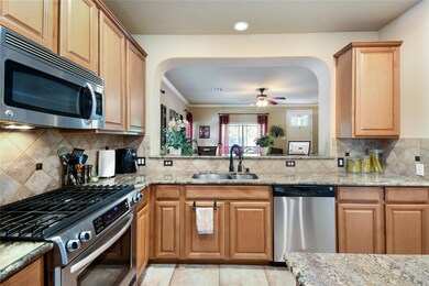 Kitchen with a sink, light stone counters, arched