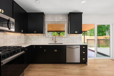 Kitchen with dark cabinetry, stainless steel appl