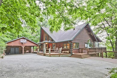 View of front with large front deck and wrap-around deck and two car carport to the left.