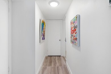 Corridor with a textured ceiling and light wood-style floors